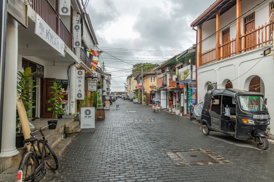 Scenic view of a cobblestone street with a black tuk-tuk in urban setting