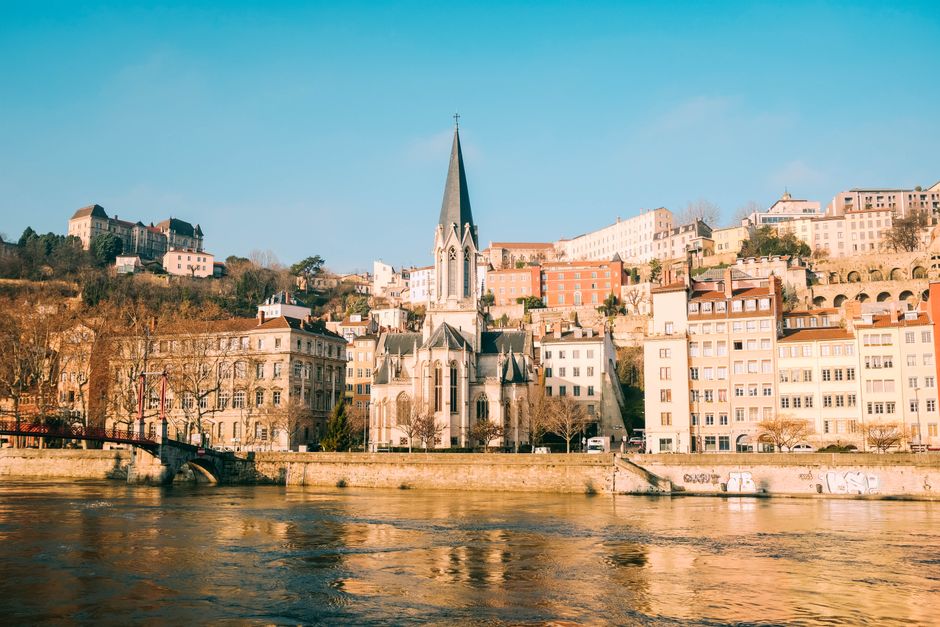 Scenic view of a historic church along the river with colorful buildings and clear sky
