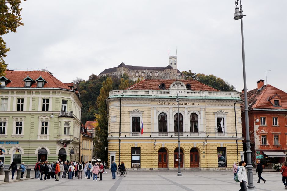 Scenic view of historical Ljubljana Castle from a bustling city square with architectural buildings