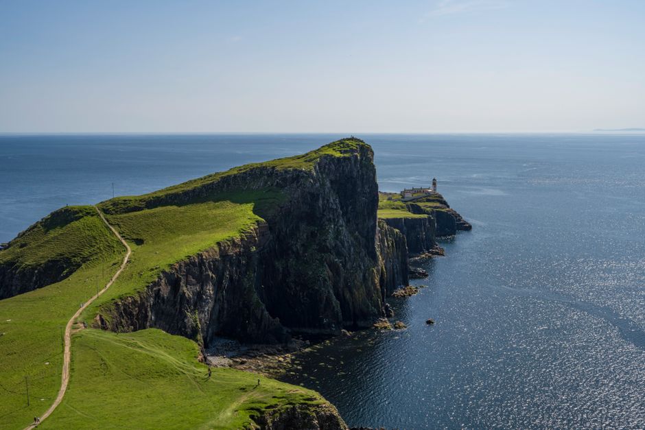 Scenic view of Neist Point cliffs and lighthouse in Scotland under a clear blue sky