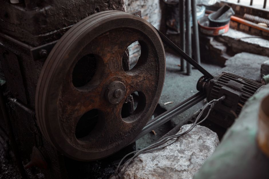 Close-up of a rusted industrial machine wheel in an old workshop setting.