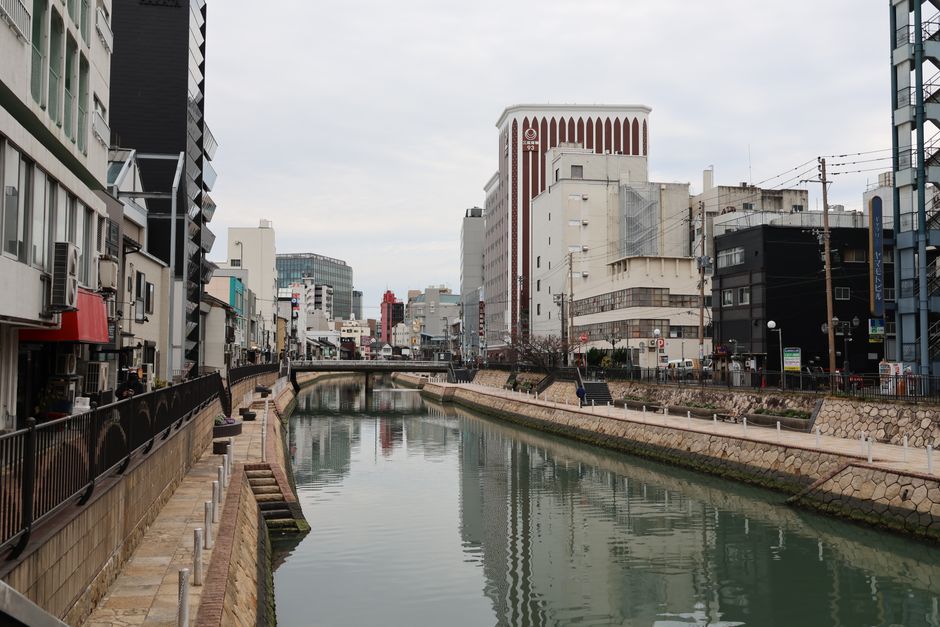Serene view of a city canal in Fukuoka, Japan, flanked by modern architecture and reflective waters