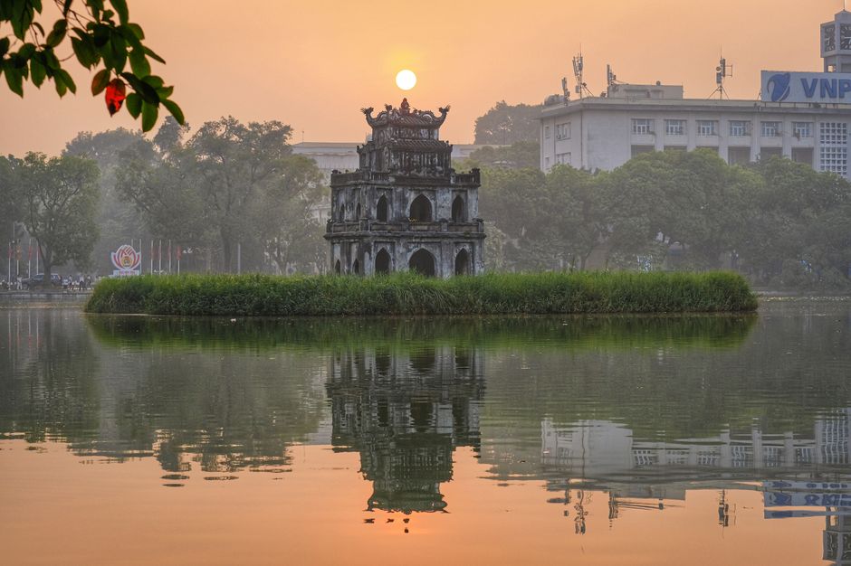 Serene view of Tortoise Tower reflecting in Hoan Kiem Lake at sunset, Hanoi