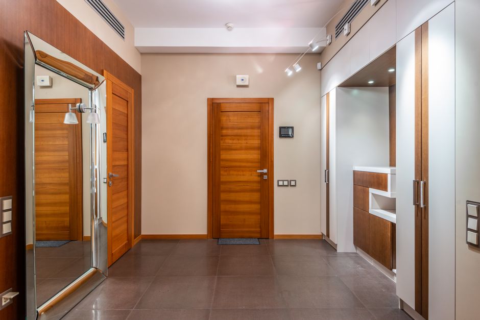 Interior of empty spacious hallway with wooden doors and large mirror in contemporary apartment