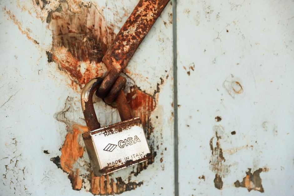 Close-up of a rusty padlock on a weathered wall, showcasing vintage charm.