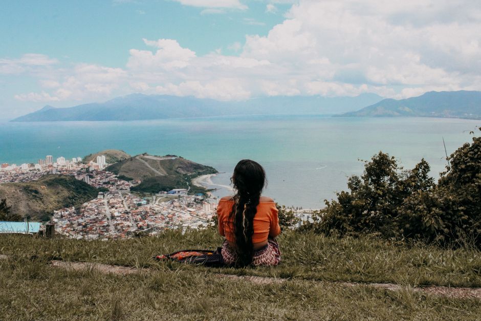 A woman with long hair enjoys the scenic ocean and city view from a hilltop in Paraty, Brazil.