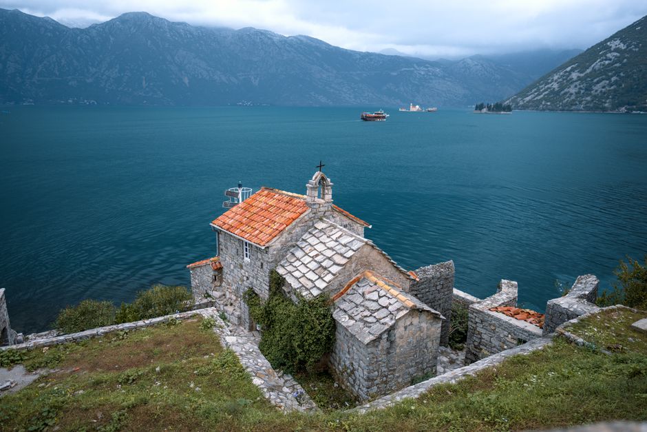 Stone church on Montenegro coast with stunning bay view, ideal for travel and landscape enthusiasts