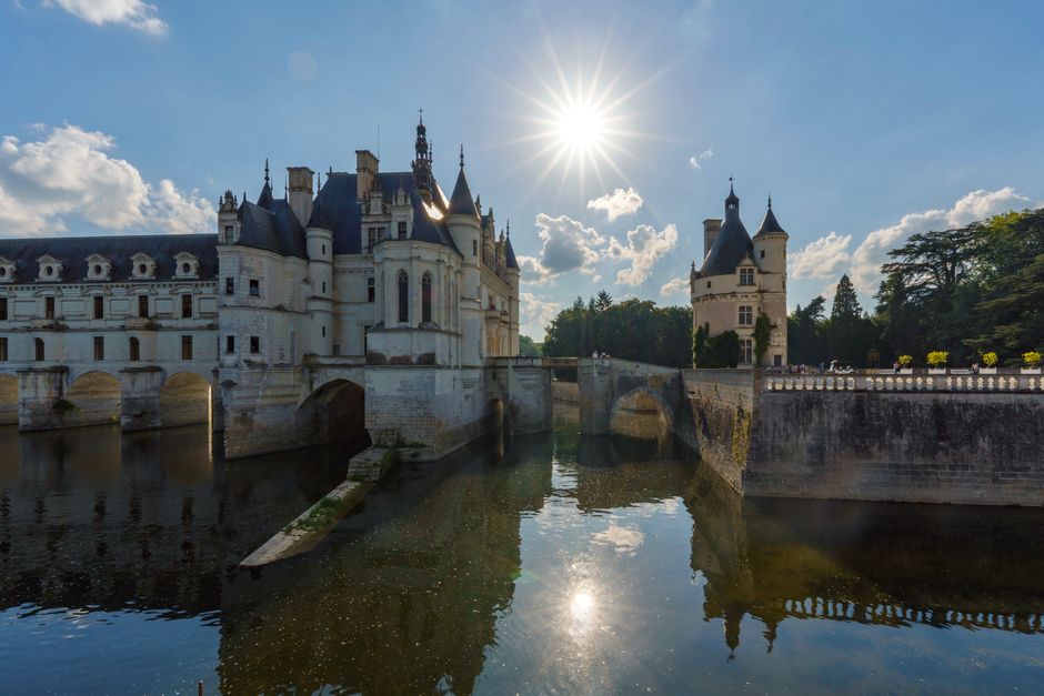 Stunning view of Château de Chenonceau with sunburst and reflections on the river Cher