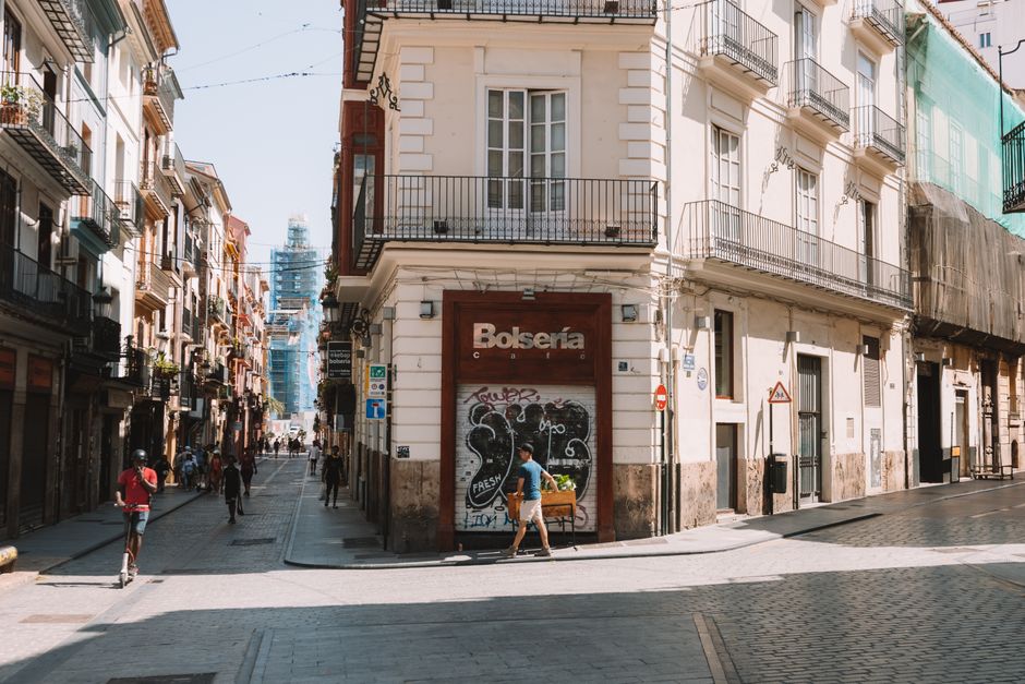 Sunlit urban street in Valencia, Spain, showcasing European architecture and city life