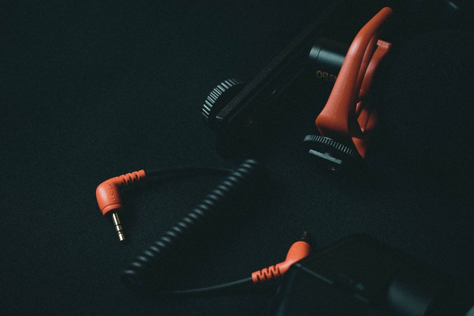 Close-up view of an orange coiled audio cable and adapter on dark background.