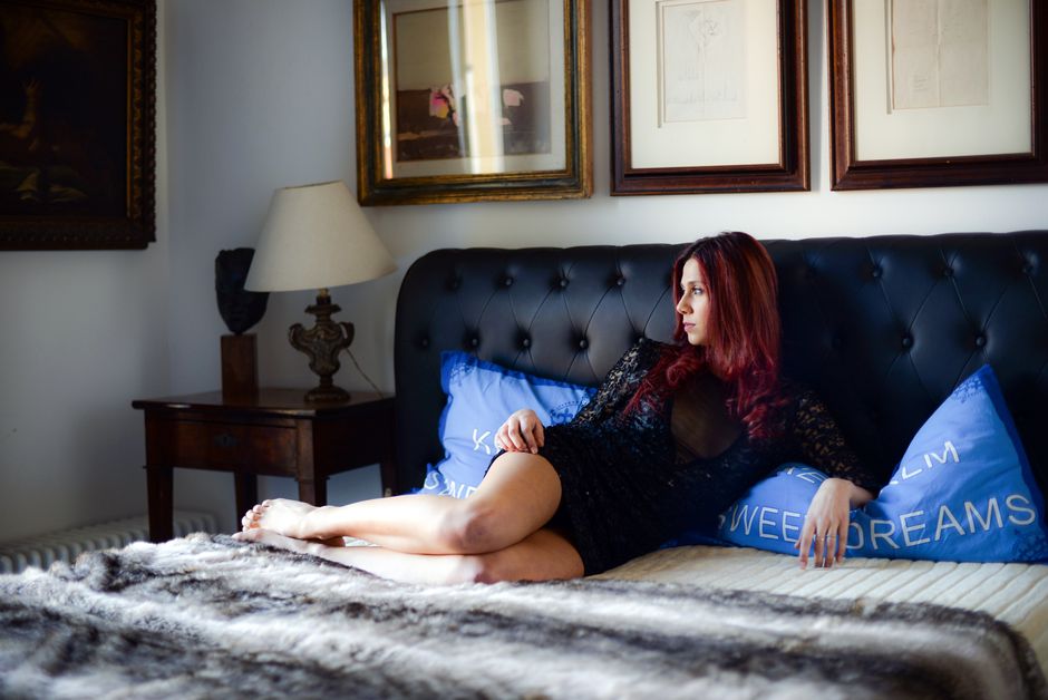 A fashionable woman with red hair lounges on a luxurious sofa, surrounded by tasteful decor.