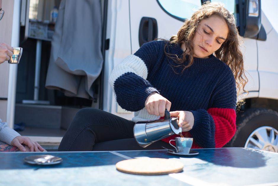A woman pouring coffee at a table outdoors, enjoying a sunny day in Portugal.