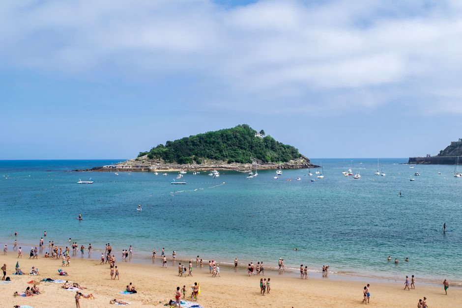 Vibrant beach scene with people enjoying the sun, sea, and a scenic island view