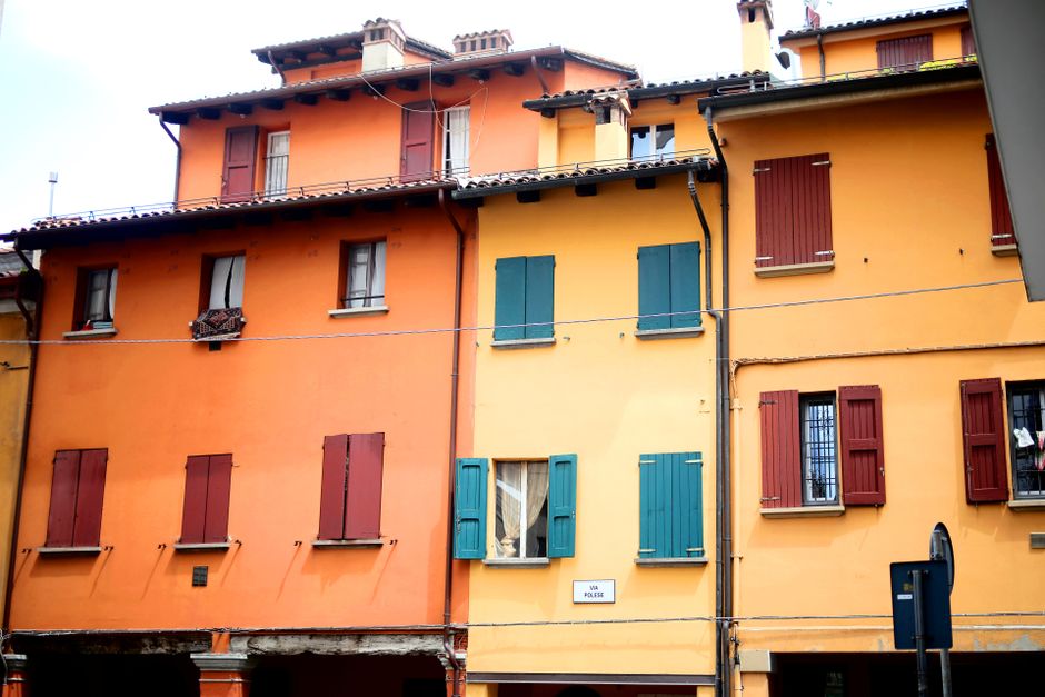 Vibrant orange and yellow buildings line a street in Bologna, showcasing classic Italian architecture