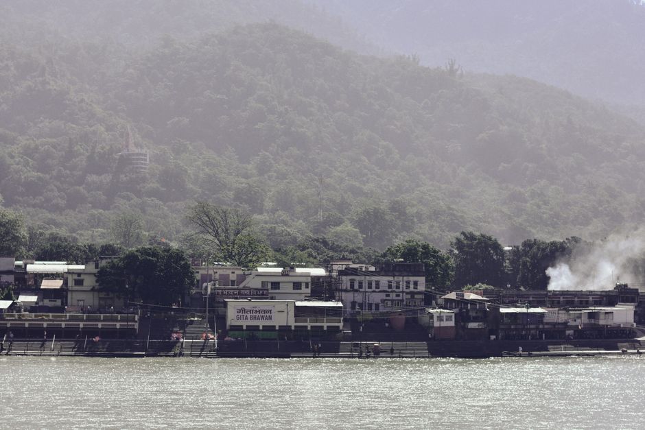 View of a tranquil riverside village with dense green hills in the background, ideal for travel and nature sce