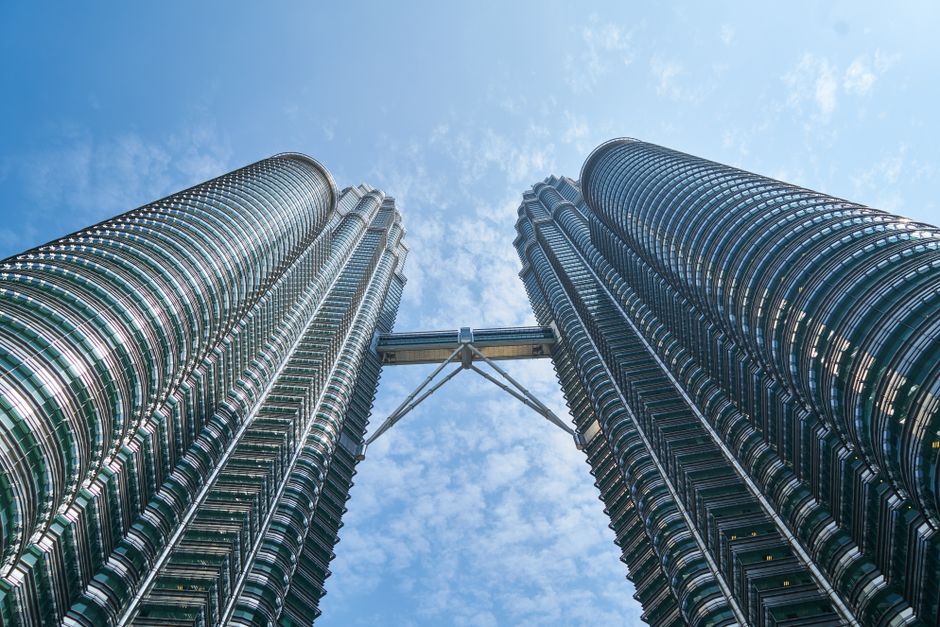View of the iconic Petronas Twin Towers reaching towards a vibrant blue sky in Kuala Lumpur