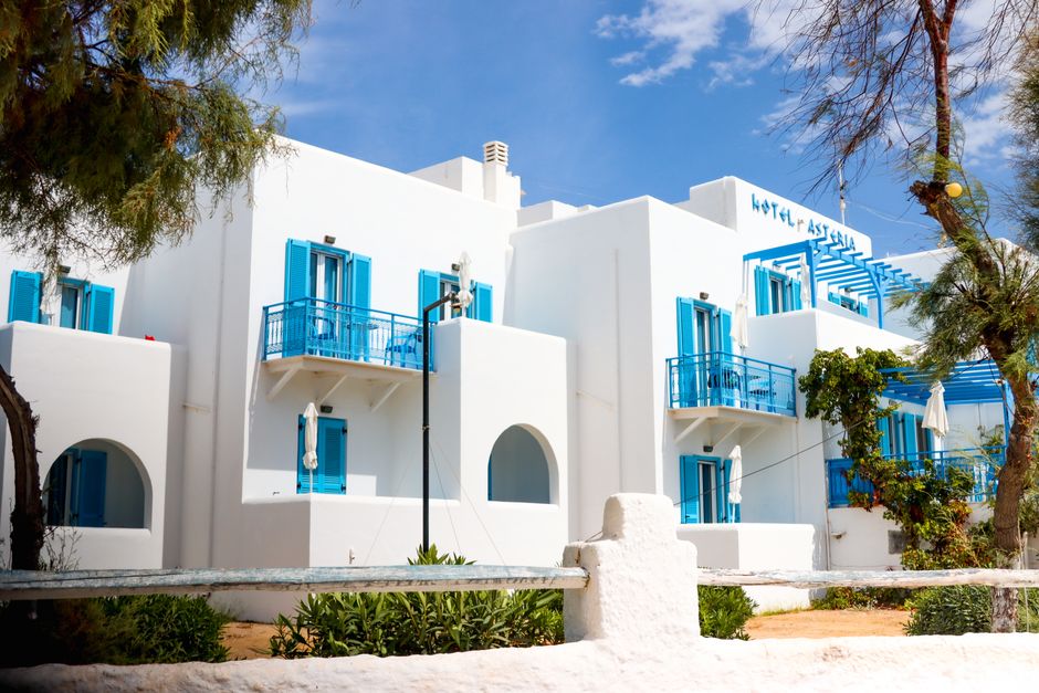 Whitewashed Greek hotel with blue shutters in Naxos under a clear sky
